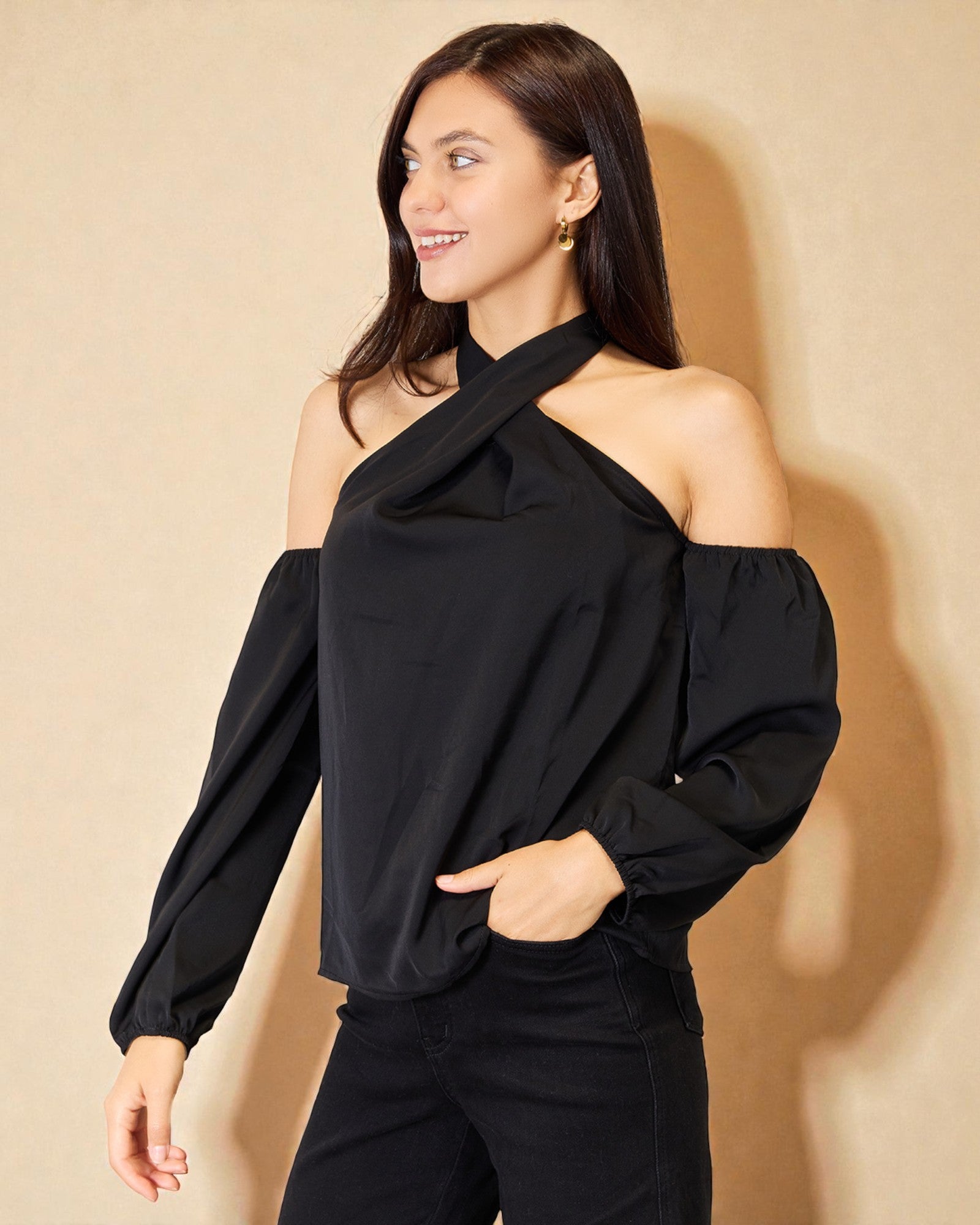 Woman wearing a black one-shoulder top against a beige background