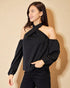 Woman wearing a black one-shoulder top against a beige background