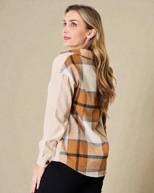 Woman wearing a plaid shirt over a beige blouse with a neutral background