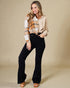 Woman wearing a plaid shirt and black pants against a beige background