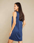 Woman wearing a blue sleeveless dress against a beige background