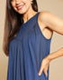 Woman wearing a blue sleeveless top against a beige background