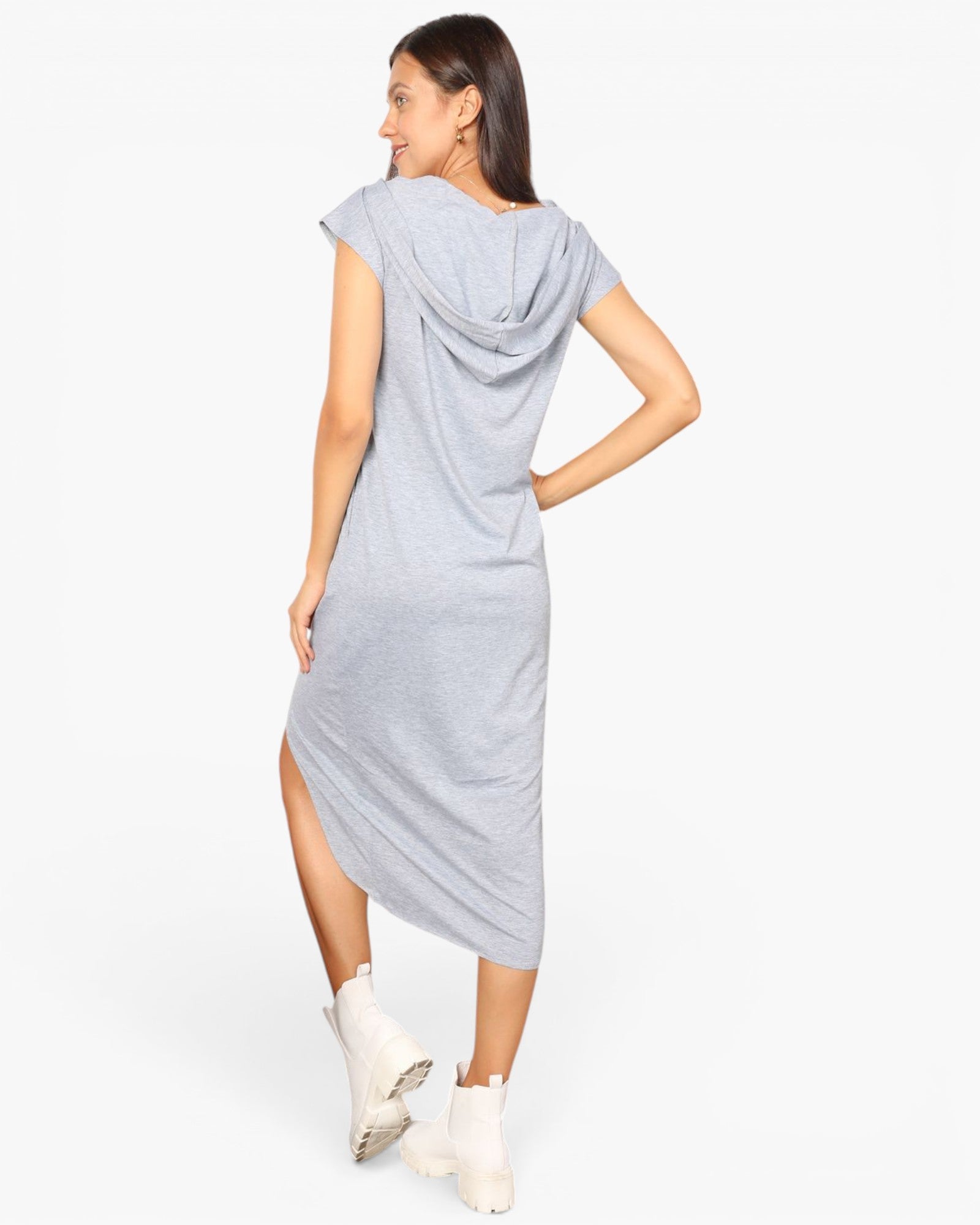 A woman modeling a light gray heathered draped midi dress with cap sleeves and a side slit, paired with white ankle boots, shown from a back-three-quarter angle against a plain white studio background.