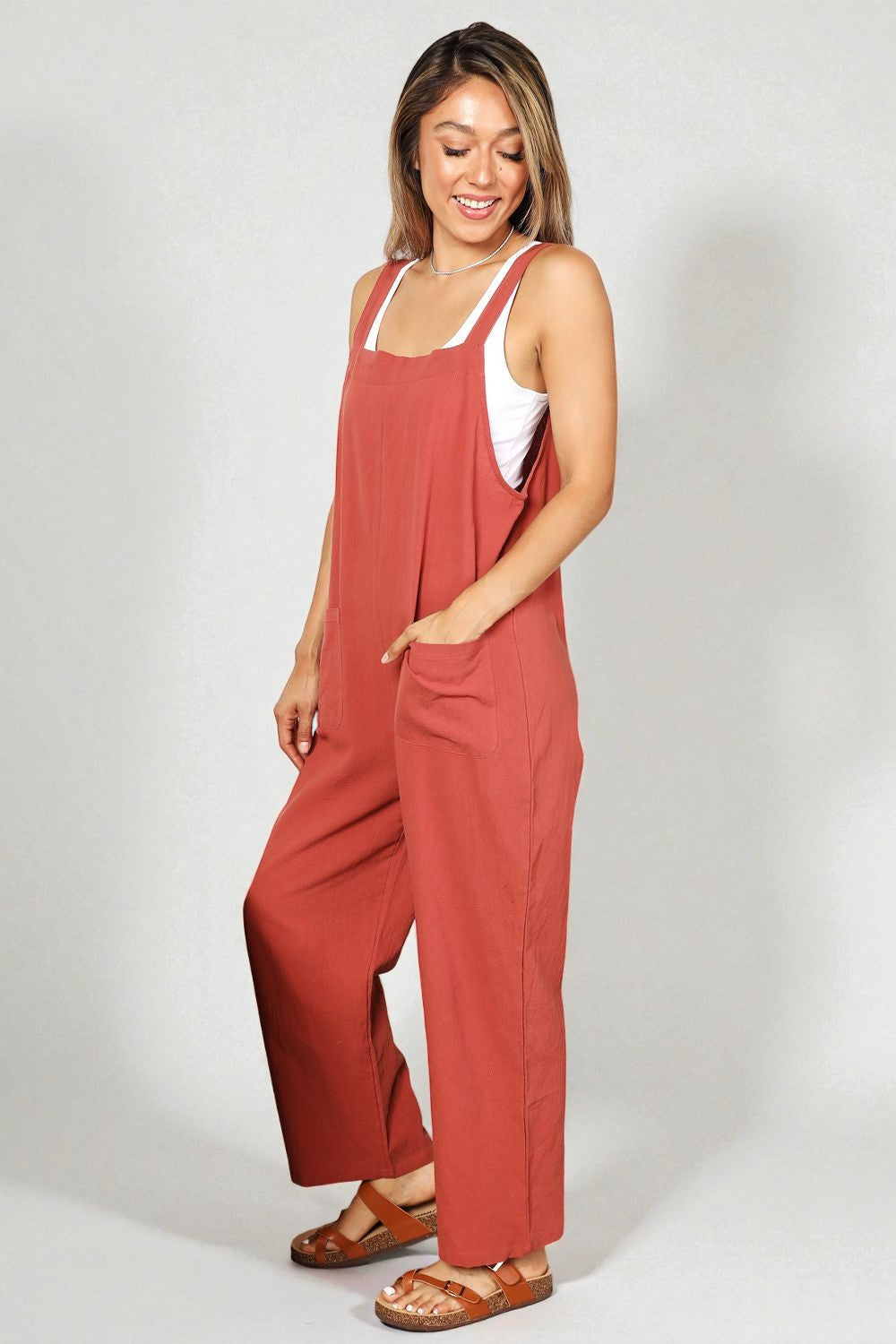 Woman wearing a red jumpsuit with a white top on a plain background