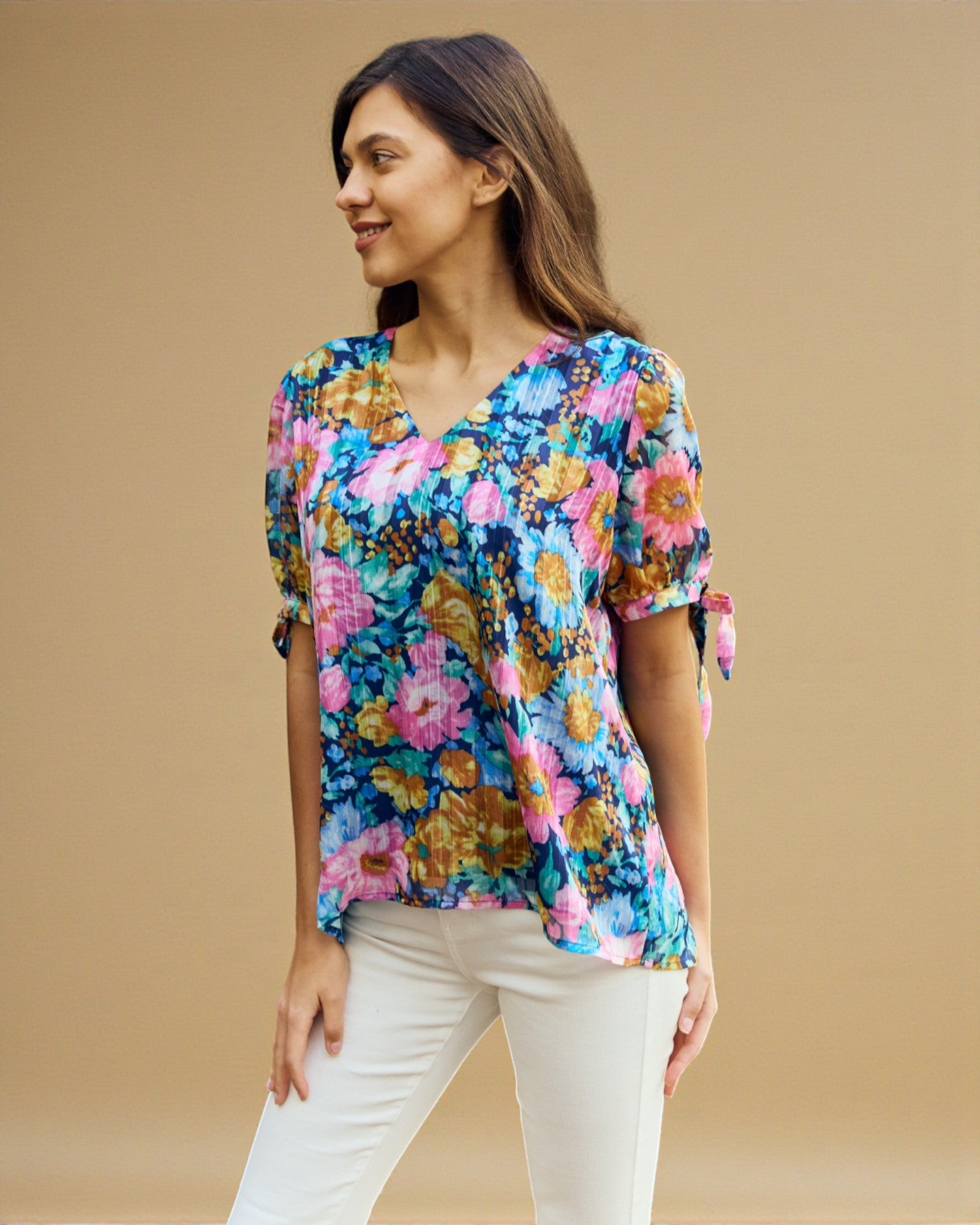 Woman wearing a colorful floral blouse against a beige background