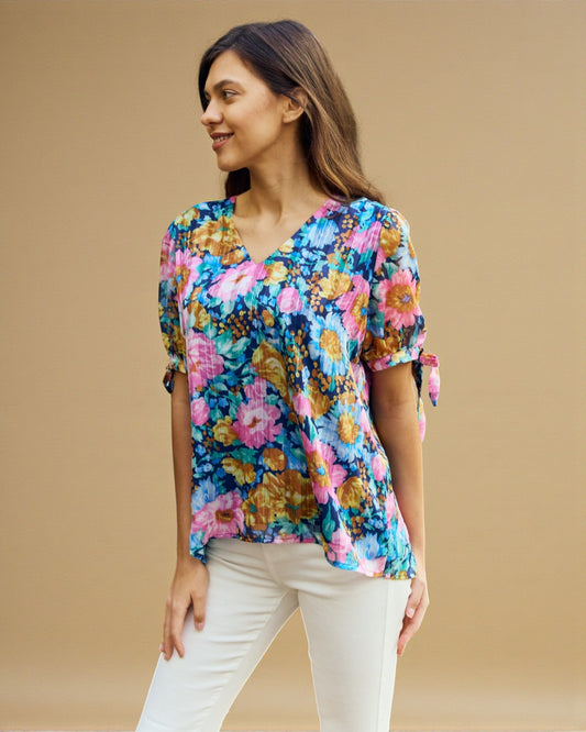 Woman wearing a colorful floral blouse against a beige background