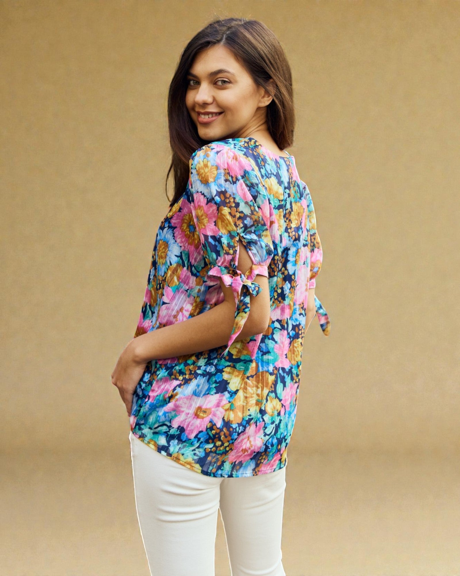 Woman wearing a colorful floral blouse against a beige background