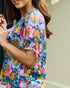 Woman wearing a colorful floral dress with a neutral background