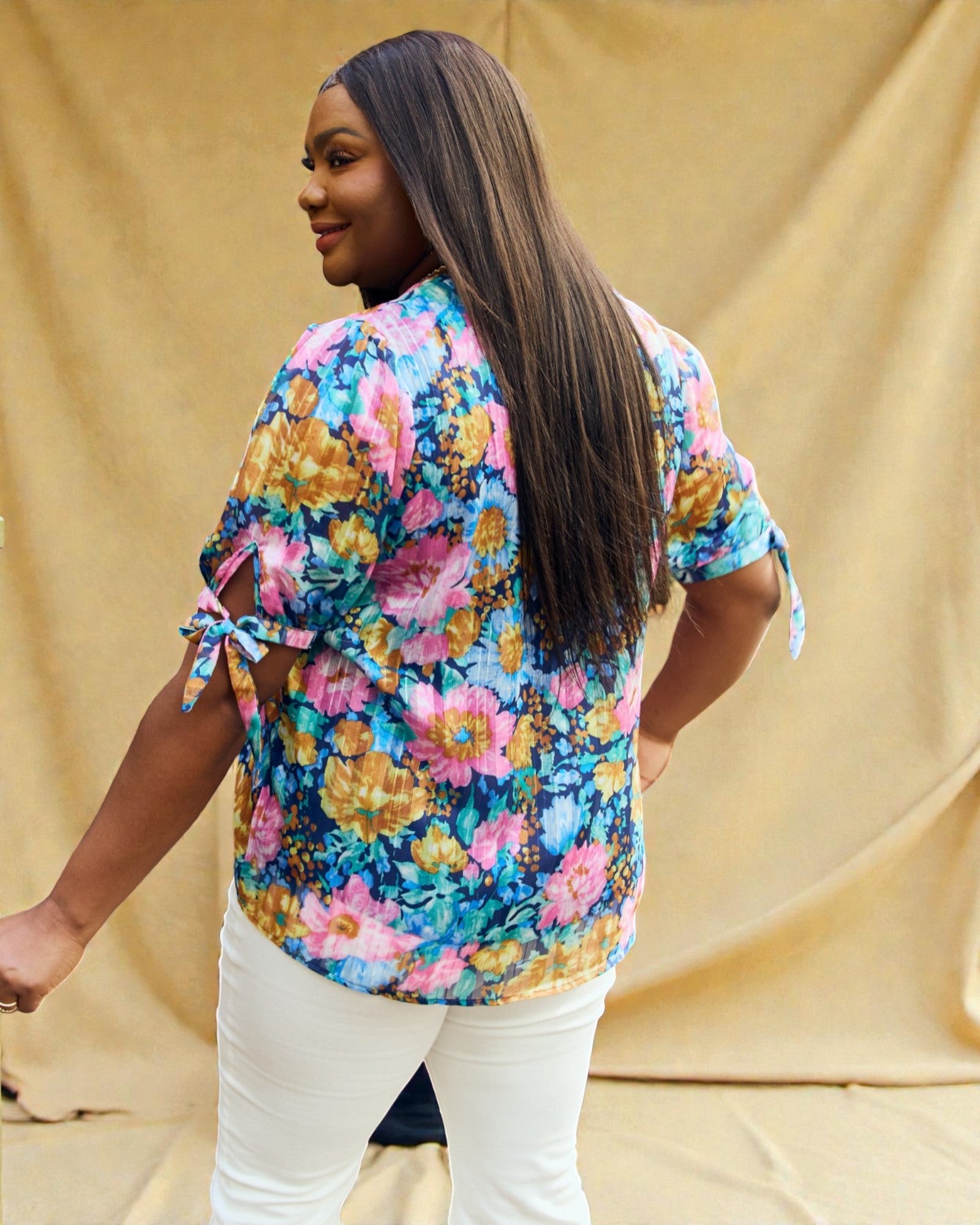 Woman wearing a colorful floral blouse against a beige background