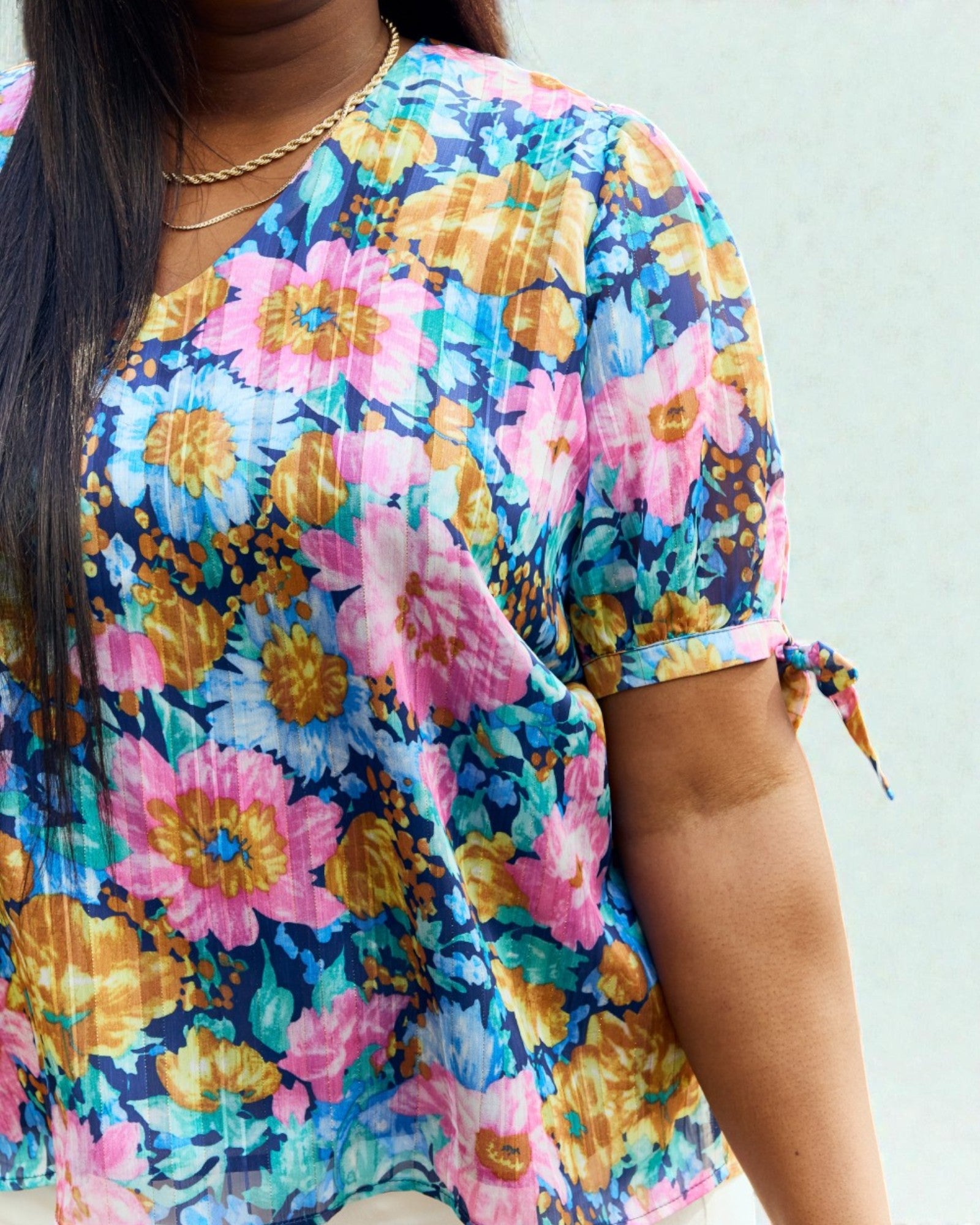 Person wearing a colorful floral shirt with a plain background