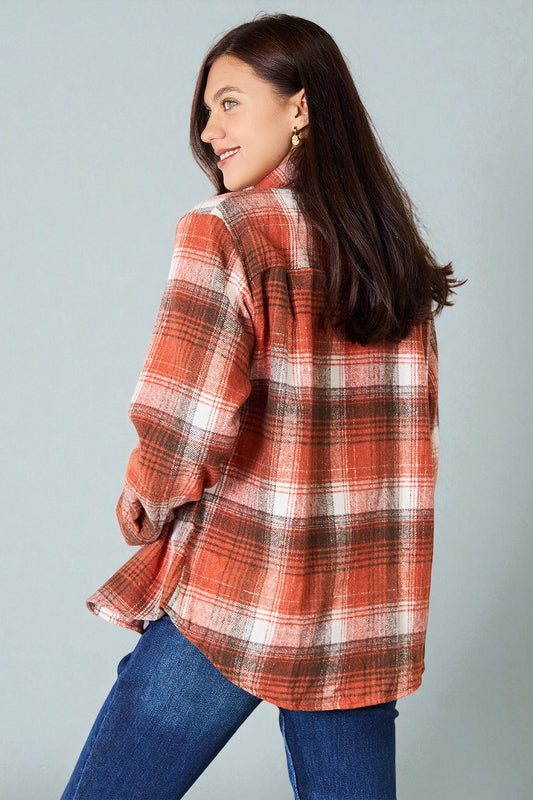 Woman wearing a red plaid shirt and blue jeans against a gray background