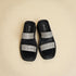 Black sandals with silver straps on a beige background