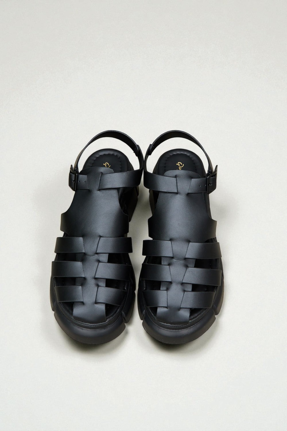 Pair of black woven sandals on a light gray background