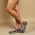 Gray sandals with black soles worn by a person on a beige background