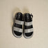 Black and gray sandals on a beige surface