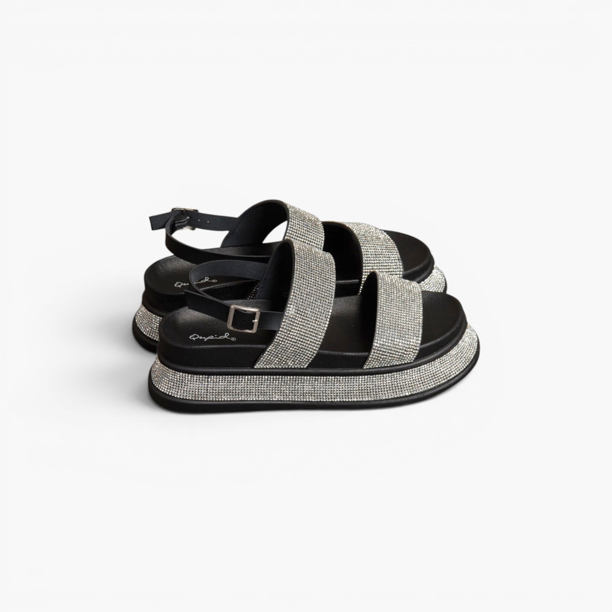 A pair of black platform sandals with wide, sparkling silver glitter straps, shown from a side profile on a clean white background.