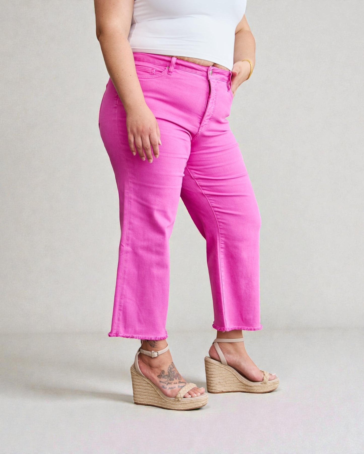 Person wearing bright pink pants and white top on a plain background