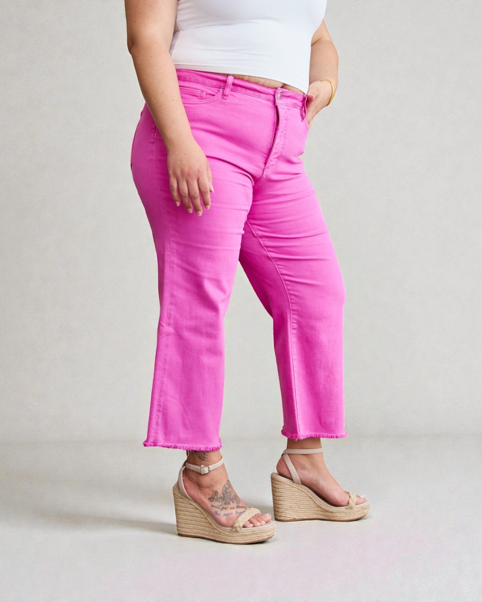 Person wearing bright pink pants and white top on a plain background