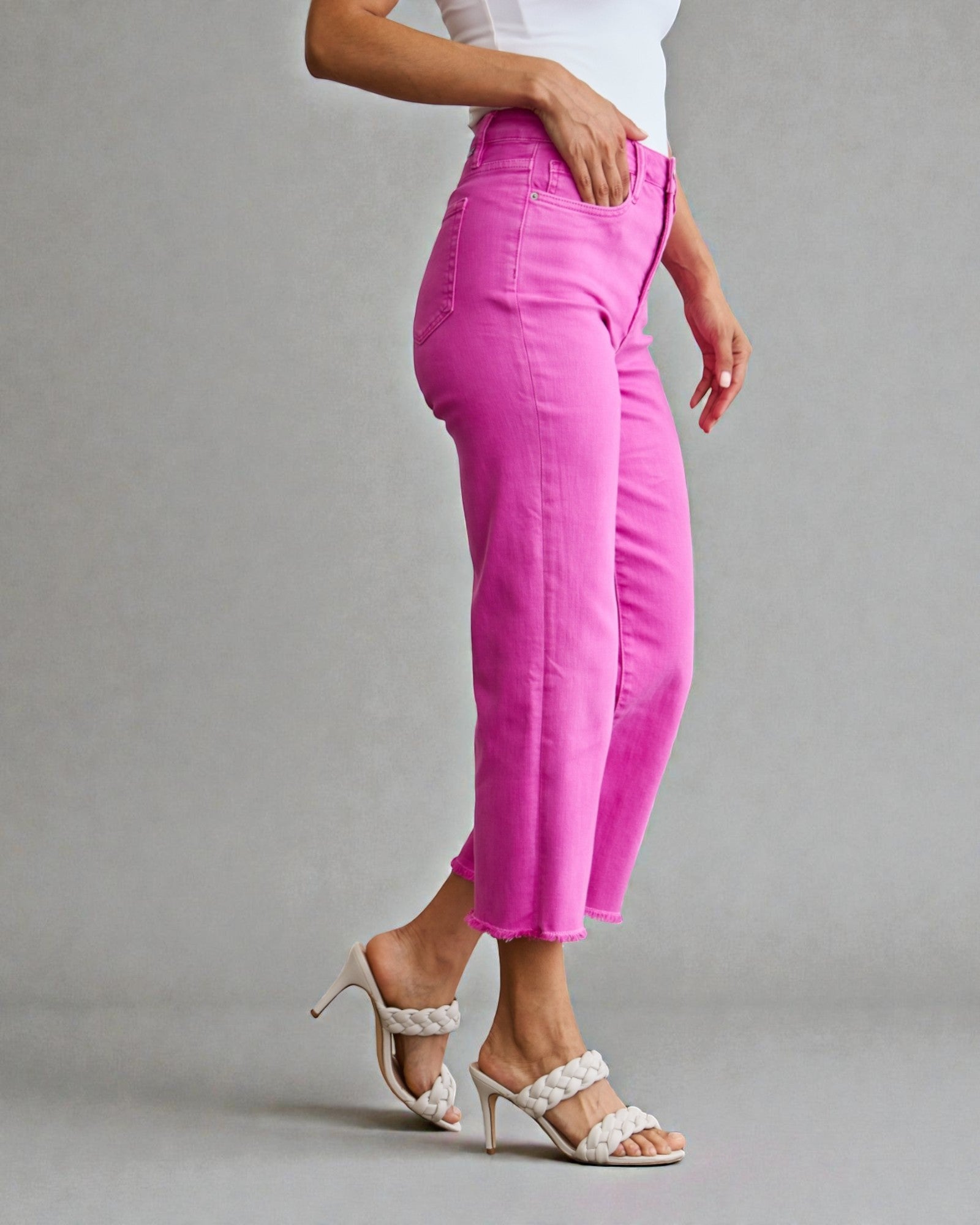 Person wearing bright pink pants and white shoes on a gray background