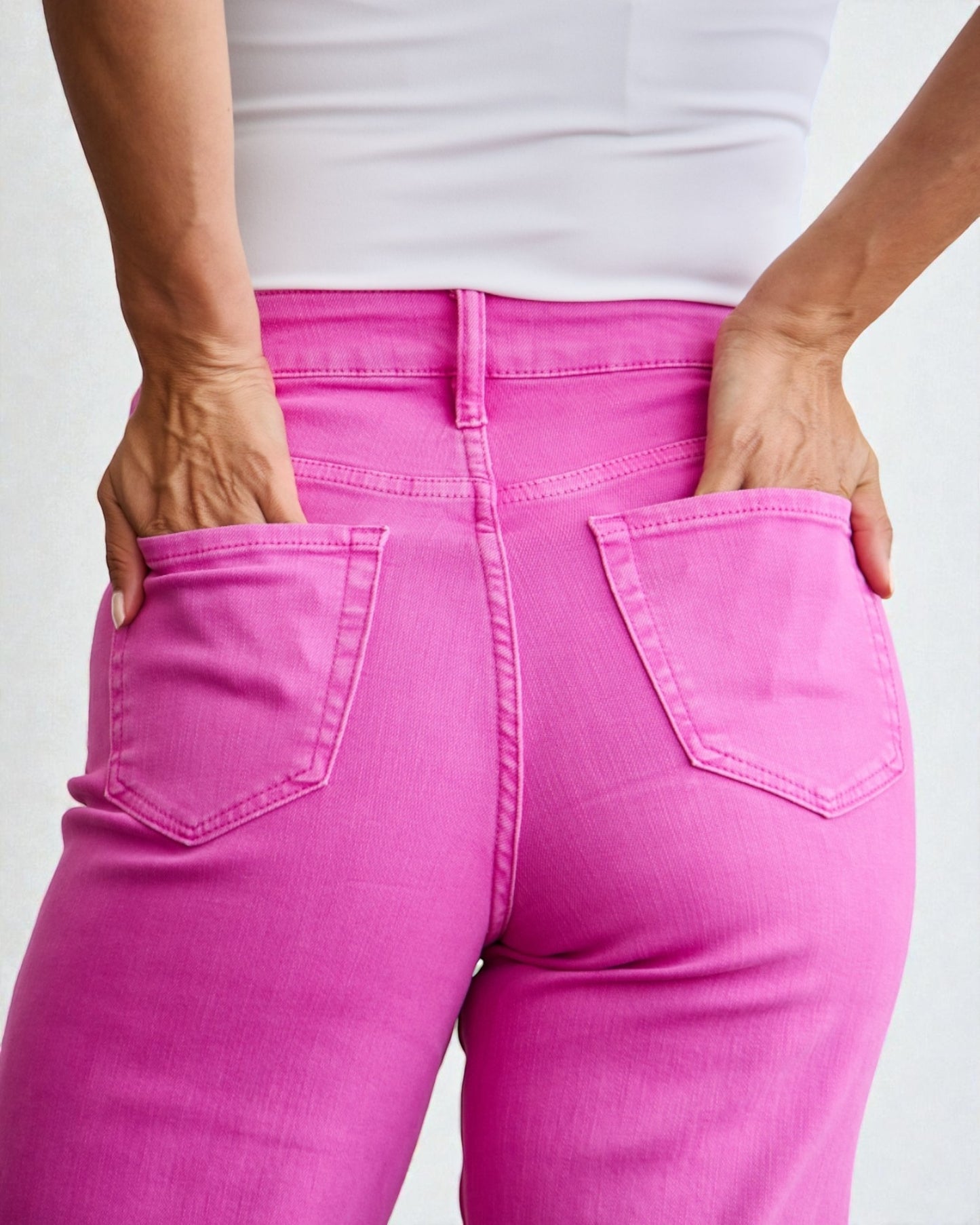 Person wearing bright pink jeans with a white background
