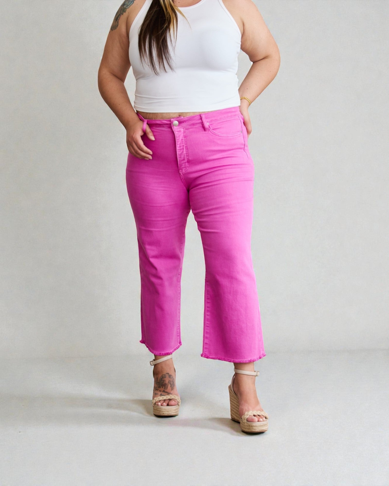 Person wearing bright pink jeans and a white top on a plain background