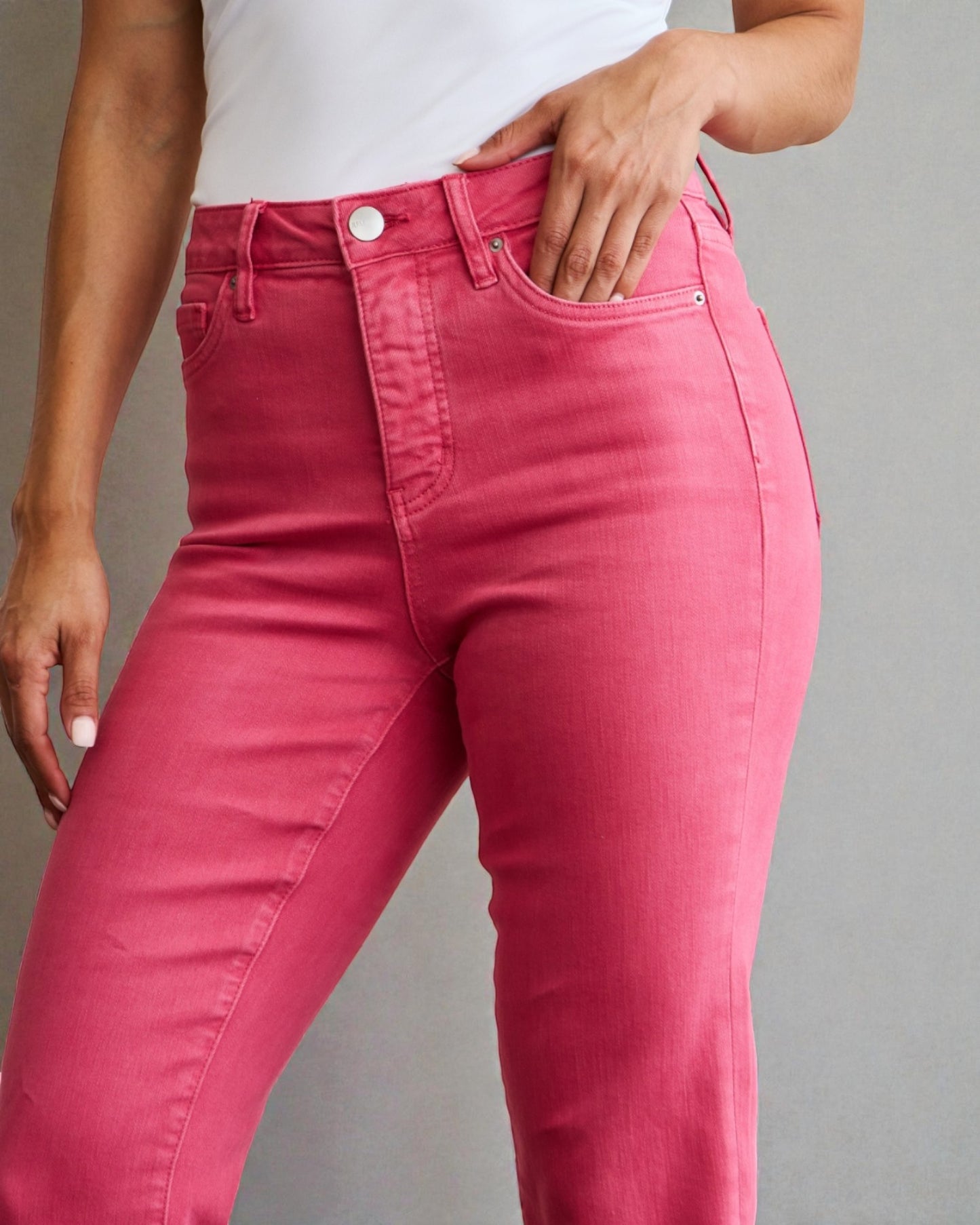 Person wearing bright pink jeans on a gray background