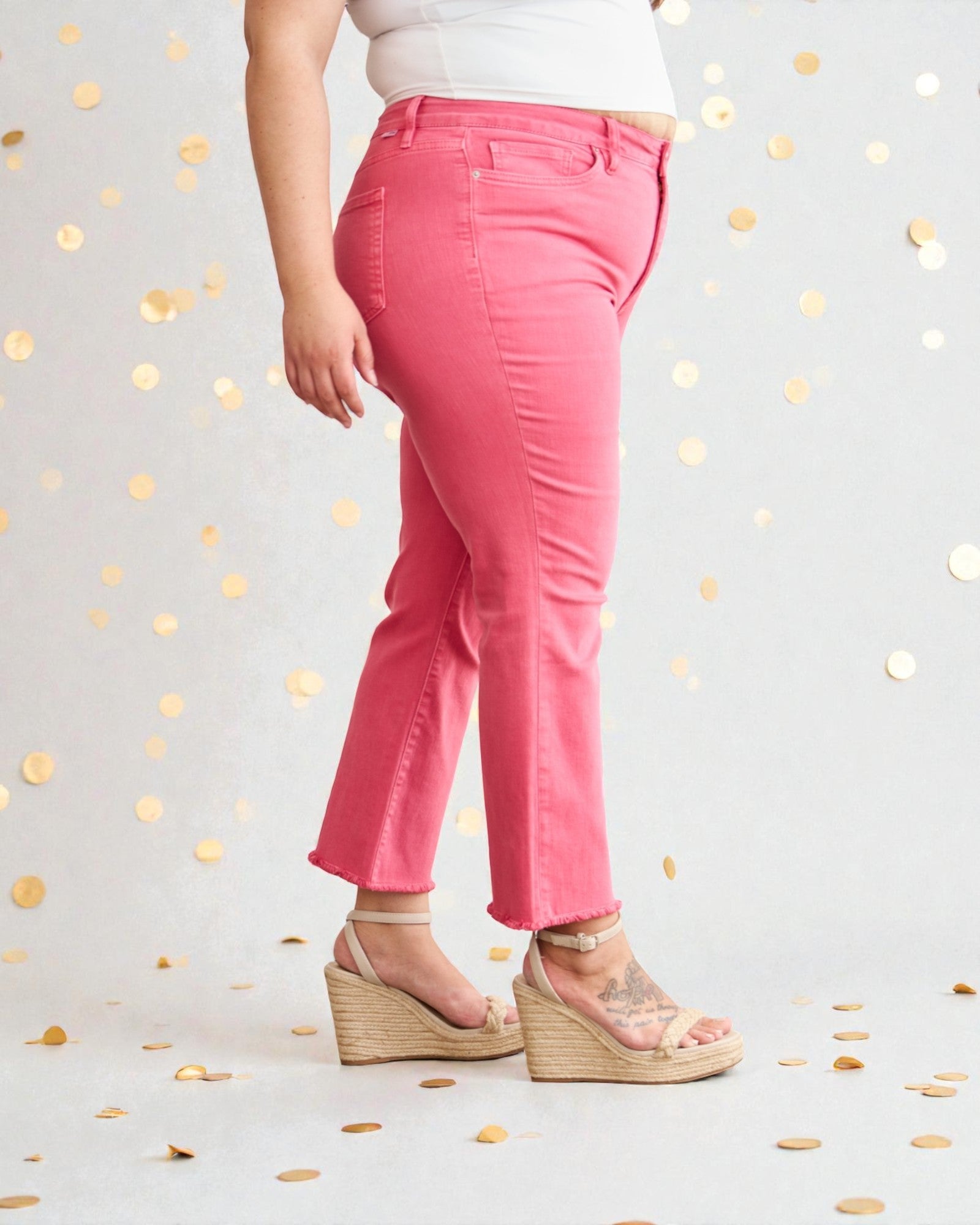 Person wearing pink pants with a white background and gold confetti
