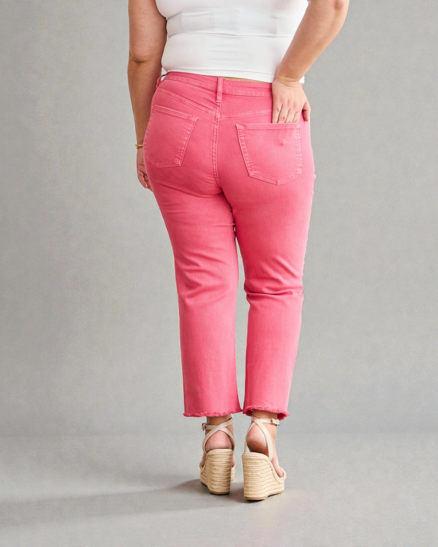 Person wearing pink pants and white top on a gray background