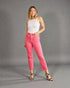 Woman wearing a white top and pink pants against a gray background