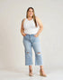 Woman wearing a white tank top and light blue jeans with a gray background