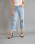Person wearing light blue ripped jeans on a gray background