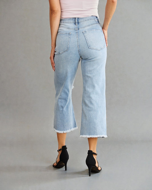 Person wearing light blue jeans and black high-heeled shoes on a gray background