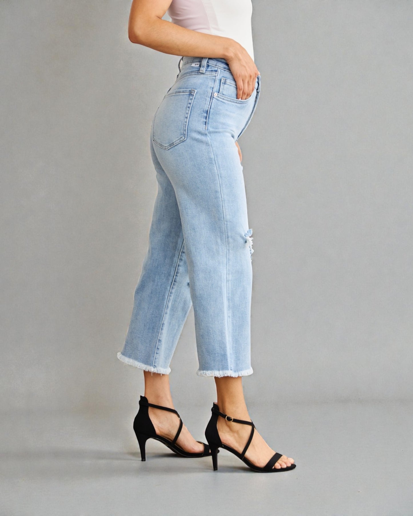 Light blue jeans worn by a person on a gray background