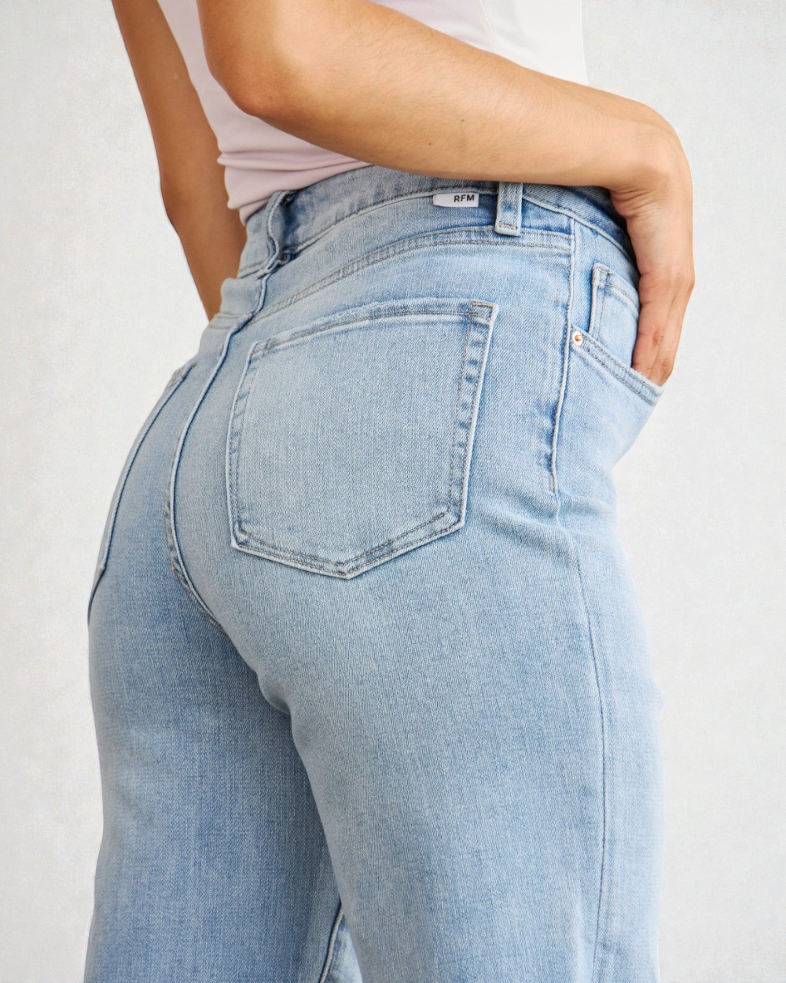 Light blue jeans worn by a person on a plain background