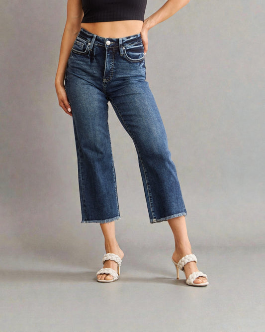 Person wearing blue jeans and a black top on a gray background