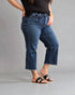 Person wearing blue jeans and black sandals on a gray background