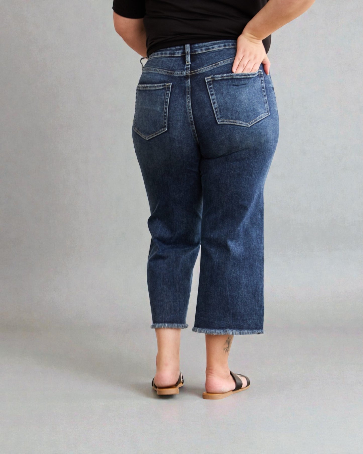 Person wearing blue jeans from behind on a gray background