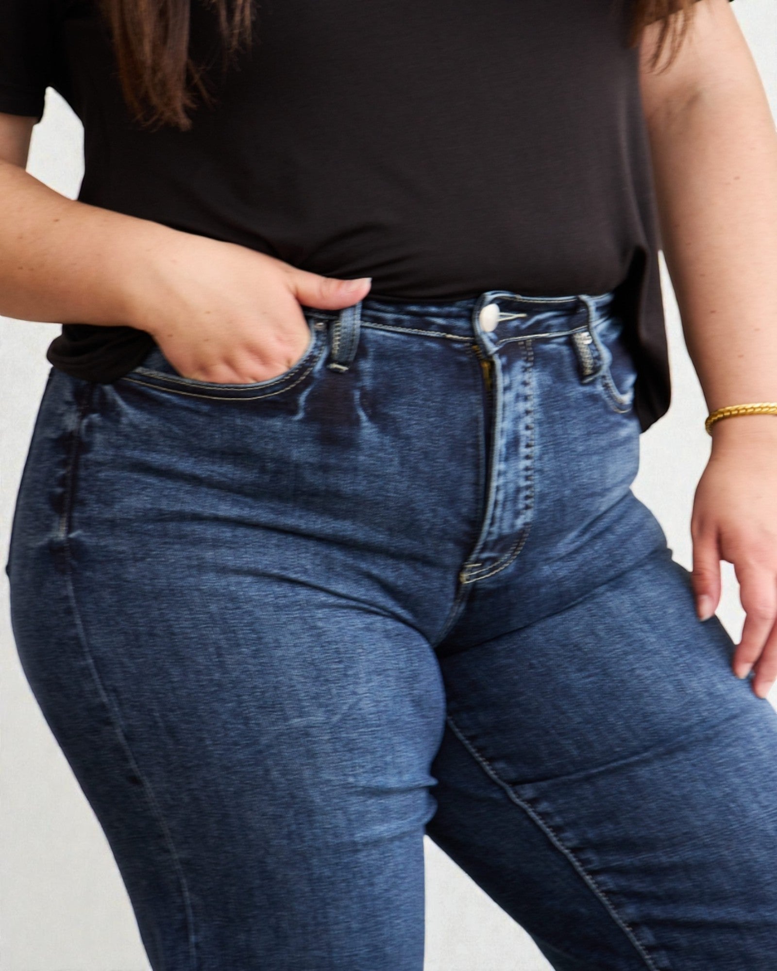 Person wearing blue jeans and a black top on a plain background