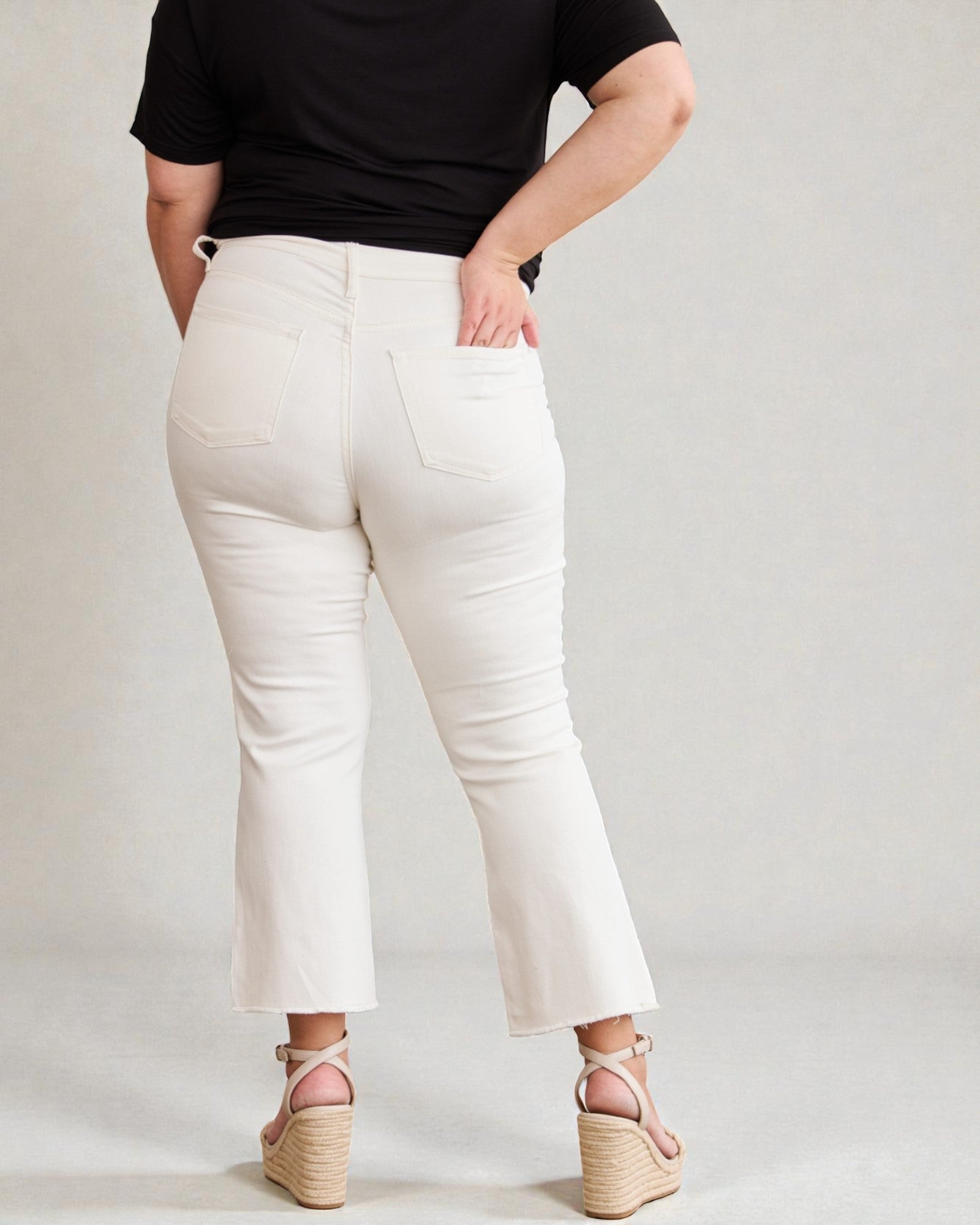 Person wearing white pants and a black top on a plain background