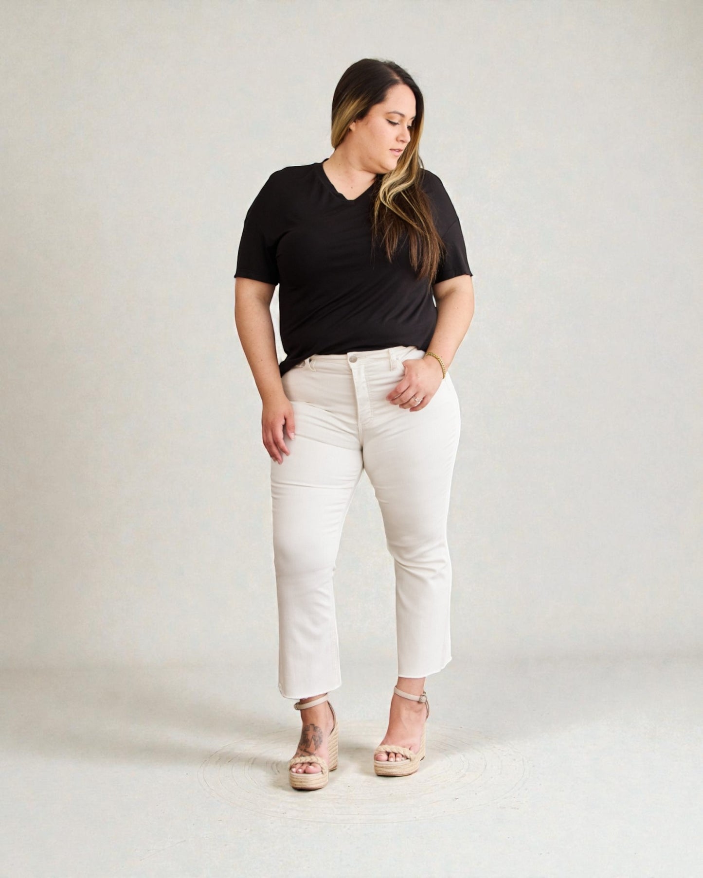 Woman wearing a black t-shirt and white pants on a plain background