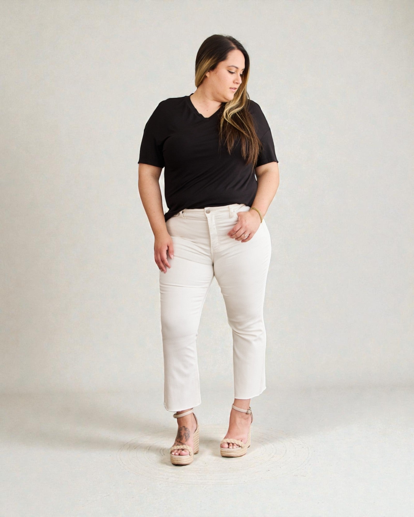 Woman wearing a black t-shirt and white pants on a plain background