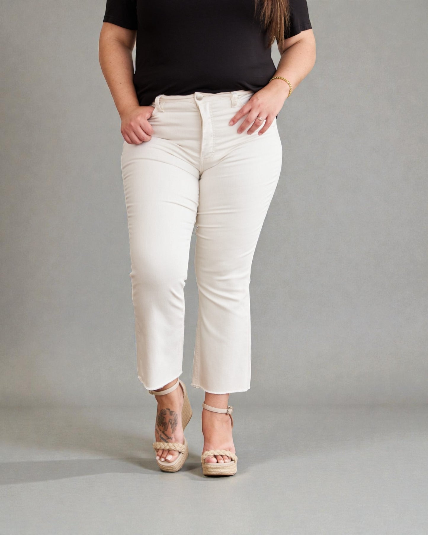 Person wearing white pants and a black top on a gray background