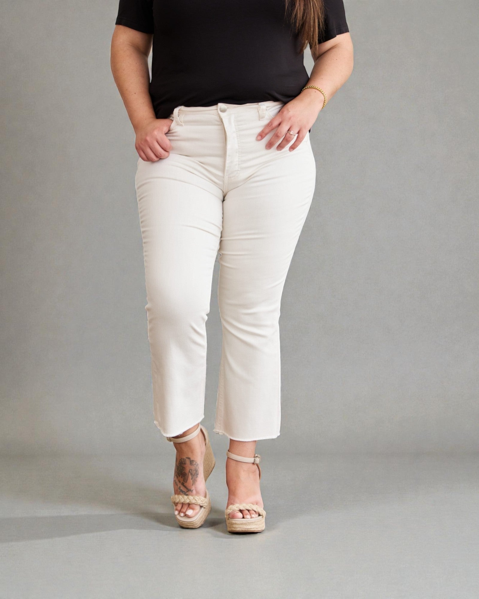 Person wearing white pants and a black top on a gray background