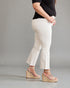 Person wearing white pants and beige wedge sandals on a gray background