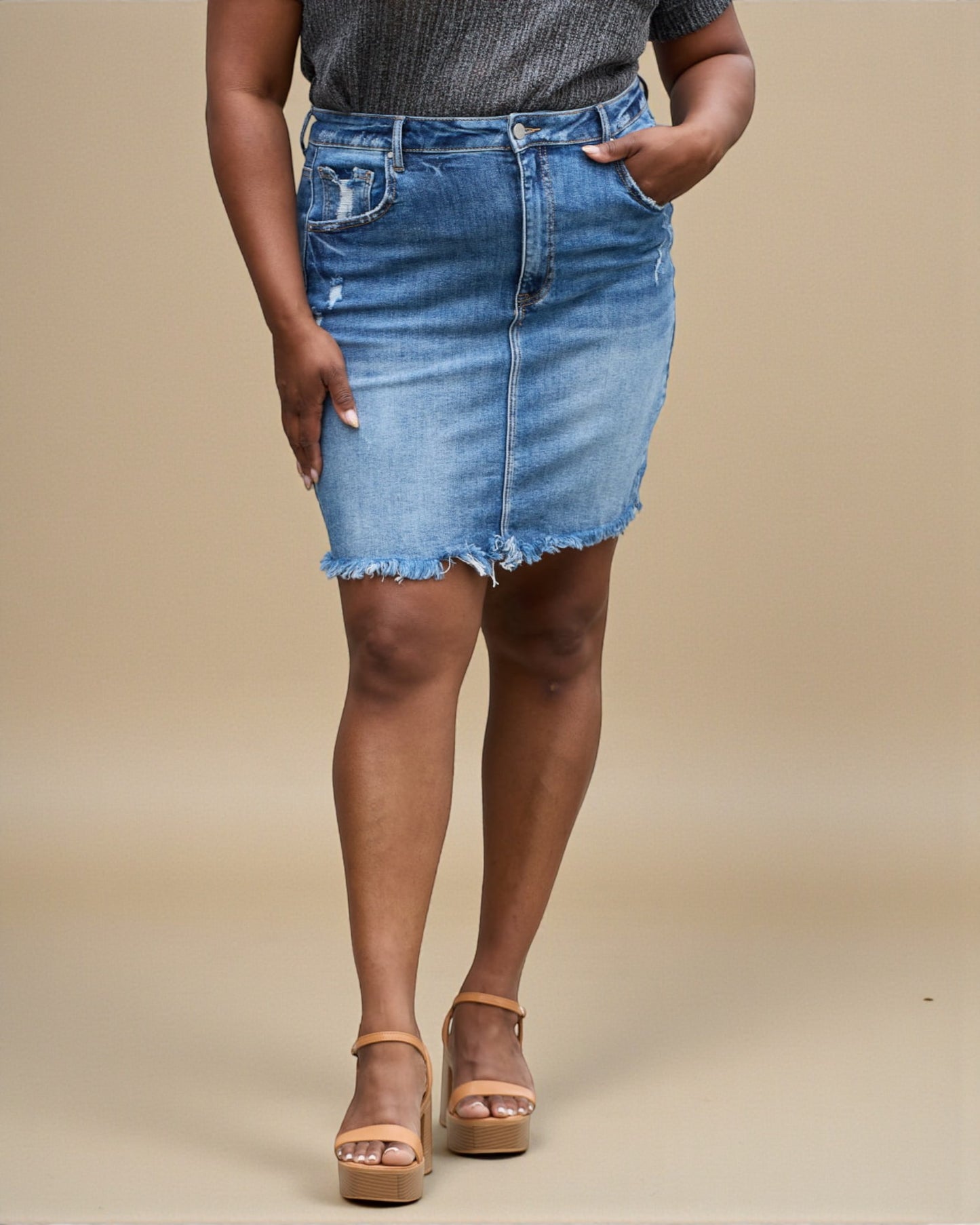 Person wearing a blue denim skirt on a beige background