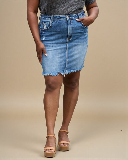 Person wearing a blue denim skirt on a beige background