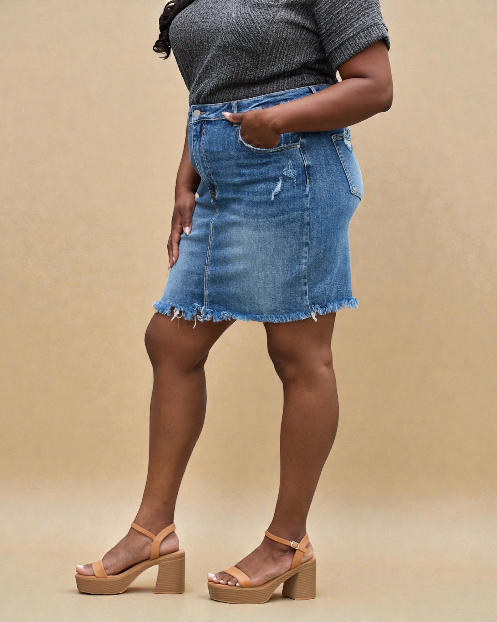 Person wearing a blue denim skirt on a beige background