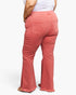 A person shown from the back wearing coral pink flared jeans with a white top, photographed against a clean white studio background.