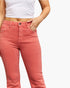 A close-up of a model wearing coral pink denim jeans with a white crop top, shown from the waist down against a plain white background.