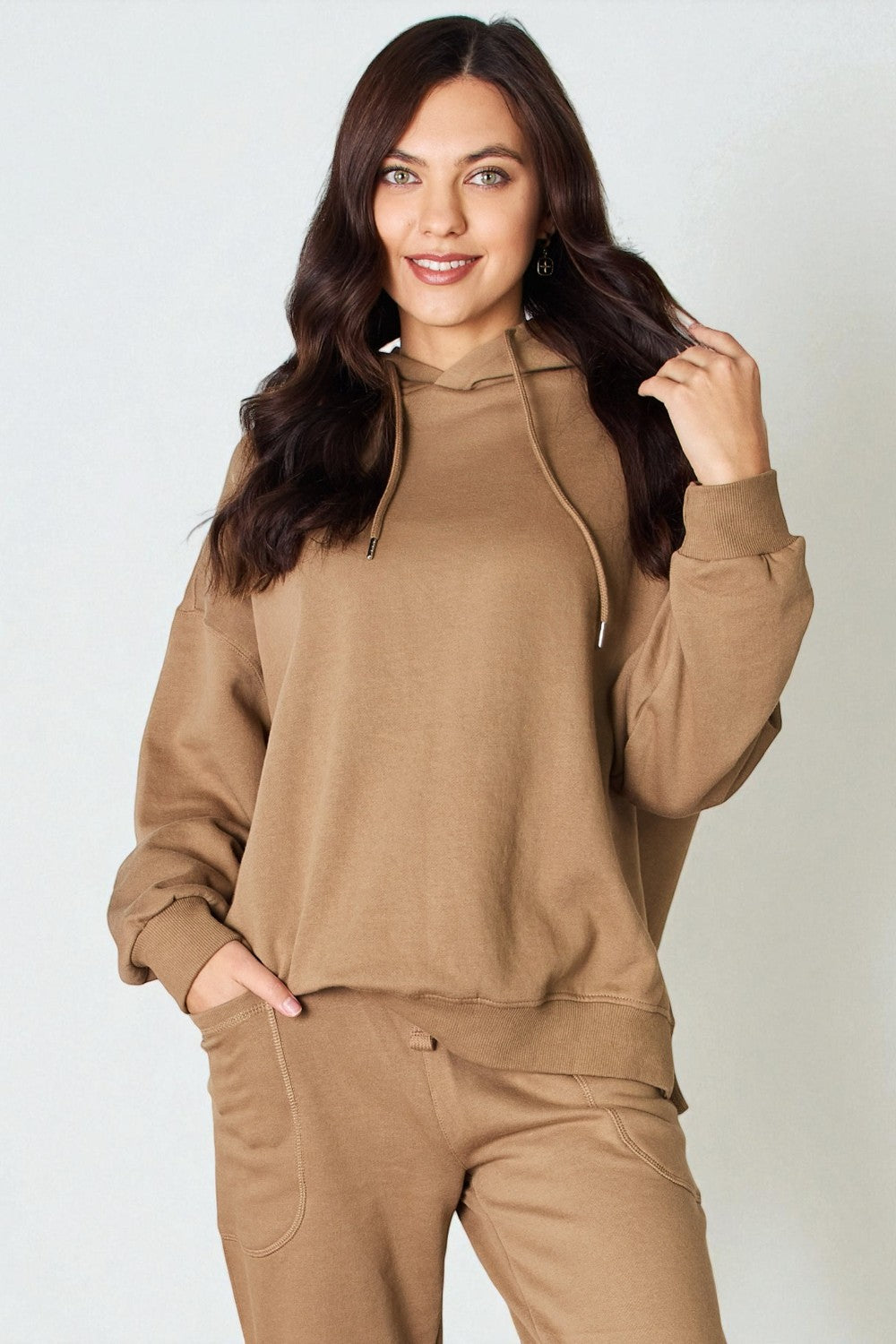 Woman wearing a brown hoodie and pants on a white background